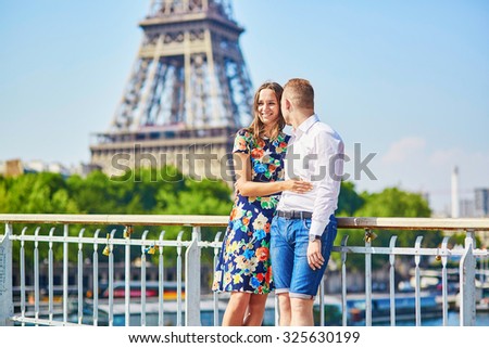 Young romantic couple having a date near the Eiffel tower on a bridge over the Seine in Paris, France