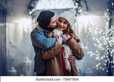 Young Romantic Couple Is Having Fun Outdoors In Winter Before Christmas. Enjoying Spending Time Together In New Year Eve. Two Lovers Are Hugging And Kissing In Saint Valentine's Day.