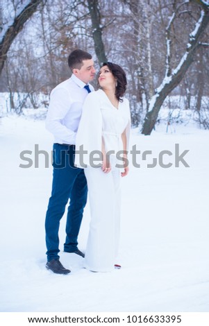 Young romantic couple is having fun outdoors in winter park, lovers are hugging and kissing in Saint Valentine's Day.