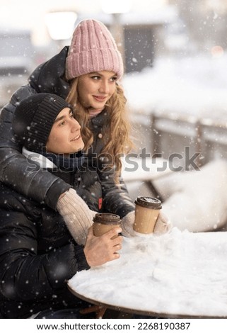 Young romantic couple is having fun outdoors in winter before Christmas. Enjoying spending time together in New Year Eve. Two lovers are hugging and kissing in Saint Valentine's Day. High quality