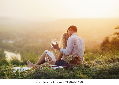 A young romantic couple having a picnic on the hill with some food and wine. - Shutterstock ID 2129664629