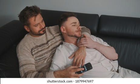 Young Romantic Gay Couple Spending Day Cuddling And Relaxing On The Couch. Different Family Lifestyle Concept. High Quality Photo