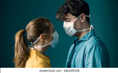 Young romantic loving couple wearing a protective face mask and staring at each other's eyes, pandemic and feelings concept
