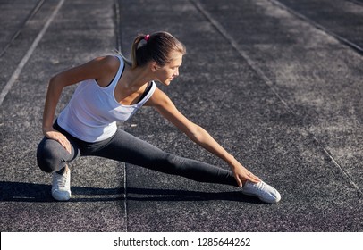 Young Runner Fit Woman Streching Before Exercises Outdoors. Athletic Female Strech After Workout Outside. Sport And People Concept.