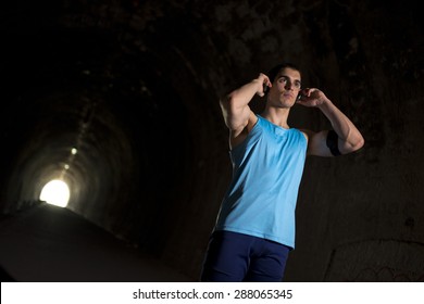 Young runner training inside a tunnel with ambient light