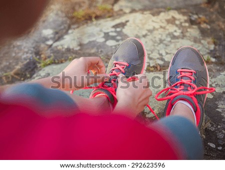Young runner tying shoelaces outside in spring nature