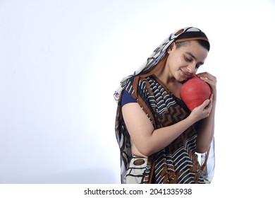 Young Rural Indian Bald Widow Saving Money Holding A Piggy Bank And Wearing A Saree Portraying Various Expressions Of The Widow Life. She Is Confident And Portraying Savings Concept.