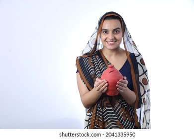 Young Rural Indian Bald Widow Saving Money Holding A Piggy Bank And Wearing A Saree Portraying Various Expressions Of The Widow Life. She Is Confident And Portraying Savings Concept.