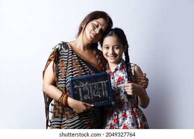 Young Rural Indian Mother And Daughter Holding A Writing Board In Hand. Mother Wearing A Saree Portraying Various Expressions Of The Rural Life. Aspirational Mother Is Working On Daughter's Education.