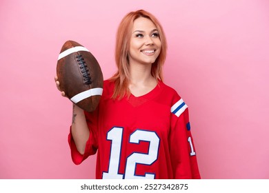 Young Russian girl playing rugby isolated on pink background looking up while smiling - Powered by Shutterstock