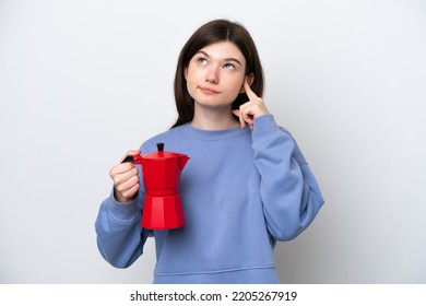 Young Russian Woman Holding Coffee Pot Isolated On White Background Having Doubts And Thinking