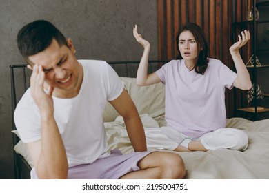 Young Sad Angry Indignant Mad Displeased Couple Two Family Man Woman She He 20s Wearing T-shirt Pajama Spread Hands Sit In Bed Spend Time Together In Bedroom Home In Own Room Hotel Real Estate Concept