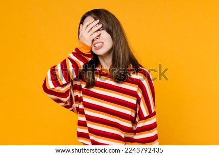 Young sad ashamed caucasian woman 20s in red striped sweatshirt put hand on face facepalm epic fail mistaken omg gesture isolated on plain yellow background studio portrait. People lifestyle concept