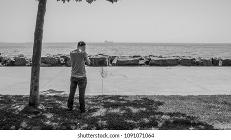 Young Sad Boy Silhouette Standing Alone, Closing / Hiding His Face With His Hands, Feeling Upset. Unhappy Man / Male Crying, Feeling Lonely At Seaside. Time To Say Goodbye. Time To Go. Missing Someone