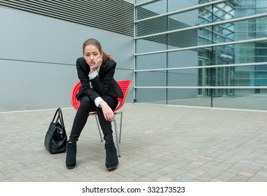 Young Sad Business Woman Sitting Alone In Modern Background.