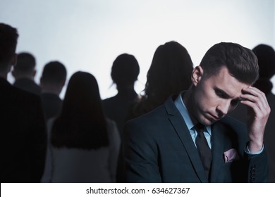 Young Sad Businessman Thinking While Standing Back To Back With A Crowd