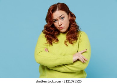 Young Sad Chubby Overweight Offended Plus Size Big Fat Fit Woman Wear Green Sweater Hold Hands Crossed Folded Look Camera Isolated On Plain Blue Background Studio Portrait. People Lifestyle Concept