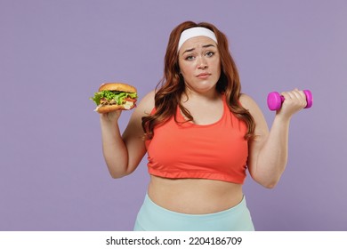 Young Sad Chubby Overweight Plus Size Big Fat Fit Woman In Red Top Warm Up Training With Dumbbells Hold Fast Food Burger Choose Isolated On Purple Background Home Gym Workout Sport Motivation Concept