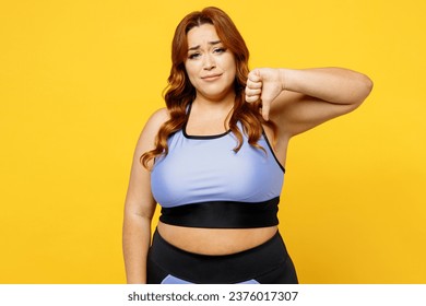 Young sad chubby overweight plus size big fat fit woman wears blue top warm up training showing thumb down dislike gesture isolated on plain yellow background studio home gym. Workout sport concept - Powered by Shutterstock