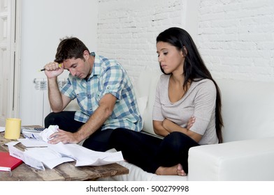 Young Sad Couple At Home Living Room Couch Calculating Monthly Expenses Worried In Stress With Bank Papers And Documents In Paying Taxes , Mortgage Debt And Cost Of Living Concept