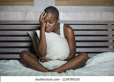 young sad and depressed black afro American woman in bed sleepless late night feeling desperate looking worried and anxious suffering depression problem and insomnia sleeping disorder