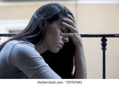 junge traurige und verzweifelte lateinische Frau, die auf dem Heimatbalkon sitzt und die zerstört aussieht und depressiv leidet Depressionen fühlt sich einsam unglücklich und hoffnungslos in geistiger Gesundheit und Krisenkonzept