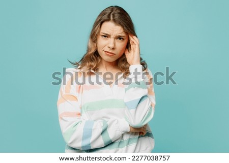 Young sad displeased dissatisfied disappointed caucasian blonde woman wearing hoody looking camera prop up head isolated on plain pastel light blue cyan background studio portrait. Lifestyle concept