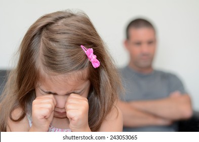 Young sad girl (age 05) crying while her desperate father sitting upset in background. Real people. Copy space