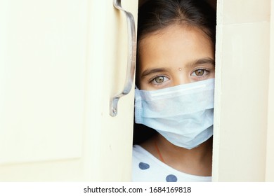 Young Sad Girl With Medical Mask Wearing Sneaking Out Through The Home Door - Concept Of Home Quarantine Due To Covid-19 Or Coronavirus Outbreak