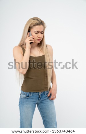 Young sad girl talking on the phone. Isolated on white background