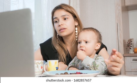 Young Sad Mom With Child Sitting At Home And Surfing The Web. Feeling Bored And Unhappy. Family Concept. 