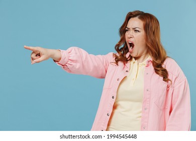 Young Sad Nervous Strict Redhead Chubby Overweight Woman 30s Wear Pink Shirt Casual Clothes Point Index Finger Aside Screaming Do It Isolated On Pastel Blue Background Studio People Lifestyle Concept