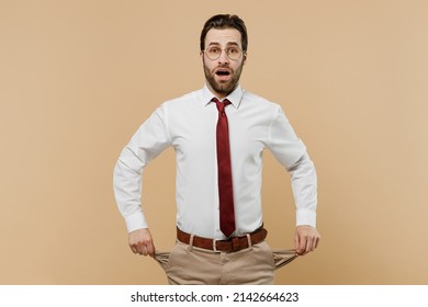 Young Sad Poor Shocked Employee Business Man Corporate Lawyer 20s Wear Classic Formal White Shirt Red Tie Glasses Work In Office Show Empty Pockets Isolated On Plain Beige Background Studio Portrait