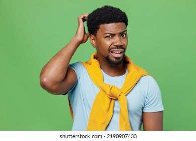 Young sad puzzled confused mistaken thoughtful man of African American ethnicity 20s wear blue t-shirt scratch hold head isolated on plain green background studio portrait. People lifestyle concept