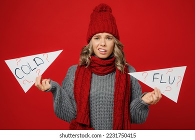 Young sad questioned woman wear grey sweater scarf hat hold card sign with cold flu title text isolated on plain red background studio. Healthy lifestyle ill sick disease treatment cold season concept - Shutterstock ID 2231750415