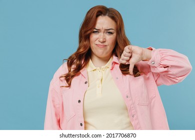 Young Sad Serious Disappointed Redhead Chubby Overweight Woman 30s Wear Pink Shirt Casual Clothes Show Thumb Down Dislike Gesture Isolated On Pastel Blue Background Studio. People Lifestyle Concept