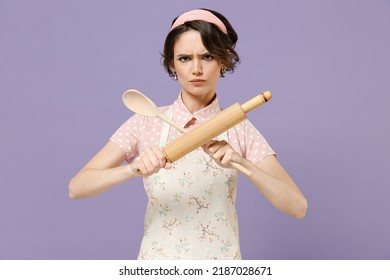 Young Sad Serious Strict Housewife Housekeeper Chef Cook Baker Woman In Pink Apron Do Stop Crossed Wooden Spoon Rolling Pin Gesture Isolated On Pastel Violet Background Cooking Food Process Concept.