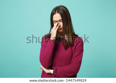 Young sad upset perplexed disturb brunette woman girl keeping eyes closed, putting hand on nose posing isolated on blue wall background studio portrait. People lifestyle concept. Mock up copy space