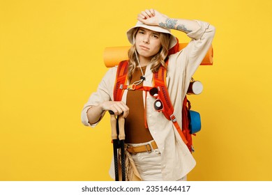 Young sad woman carry backpack with stuff mat hold trekking poles sweating isolated on plain yellow background. Tourist leads active lifestyle walk on spare time. Hiking trek rest travel trip concept - Powered by Shutterstock