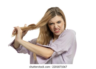 Young sad woman combs to her long wavy hair. Model with long curly hair angry combing her tangled hair.  Haircare beauty products, shampoo and lotion. Hair Care Spa and wellness