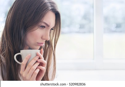 Young Sad Woman With Cup Of Coffee Or Tea. Stress, Depression, Illness Concept.