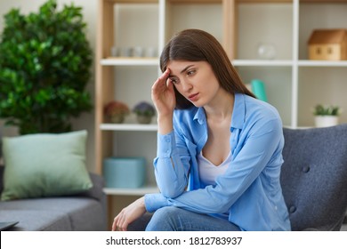 Young sad woman feeling bad and touching forehead with hand at home over room background. Negative emotions, depression, headache concept - Shutterstock ID 1812783937