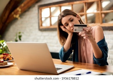 Young Sad Woman Having Problems While Using Credit Card And E-banking Over Laptop At Home.