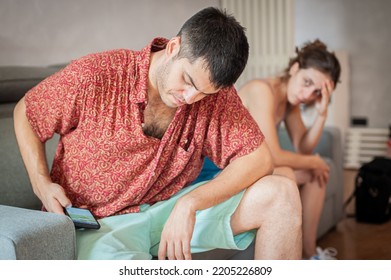 A Young Sad Woman Is Next To Her Partner Who Is Texting On The Phone With Someone, And Not Paying Attention To Her.