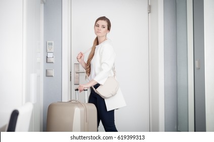 Young sad woman pulling suitcase and leaves modern hotel room