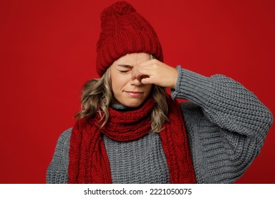 Young sad woman wear warm gray sweater scarf hat keep eyes closed rub put hand on nose isolated on plain red background studio portrait Healthy lifestyle ill sick disease treatment cold season concept - Shutterstock ID 2221050075