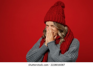 Young sad woman wear warm gray sweater scarf hat cover mouth with hands sneezy cough isolated on plain red background studio portrait. Healthy lifestyle ill sick disease treatment cold season concept - Shutterstock ID 2228018387