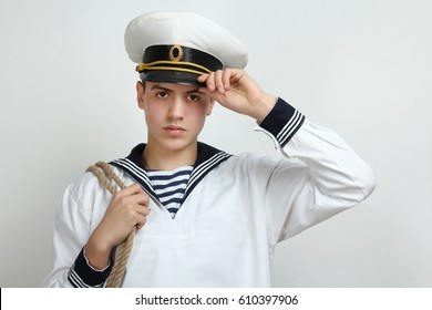 Young sailor holding his hand a cap with a rope on his shoulder on a white background - Shutterstock ID 610397906