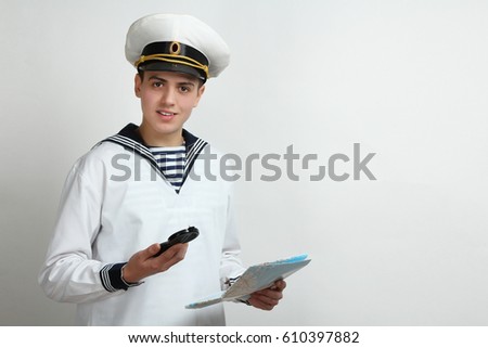 Young sailor holding a map and a compass in the hands on a white background