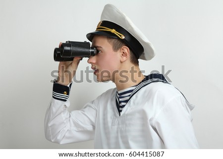 Young sailor looking through binoculars on a white background